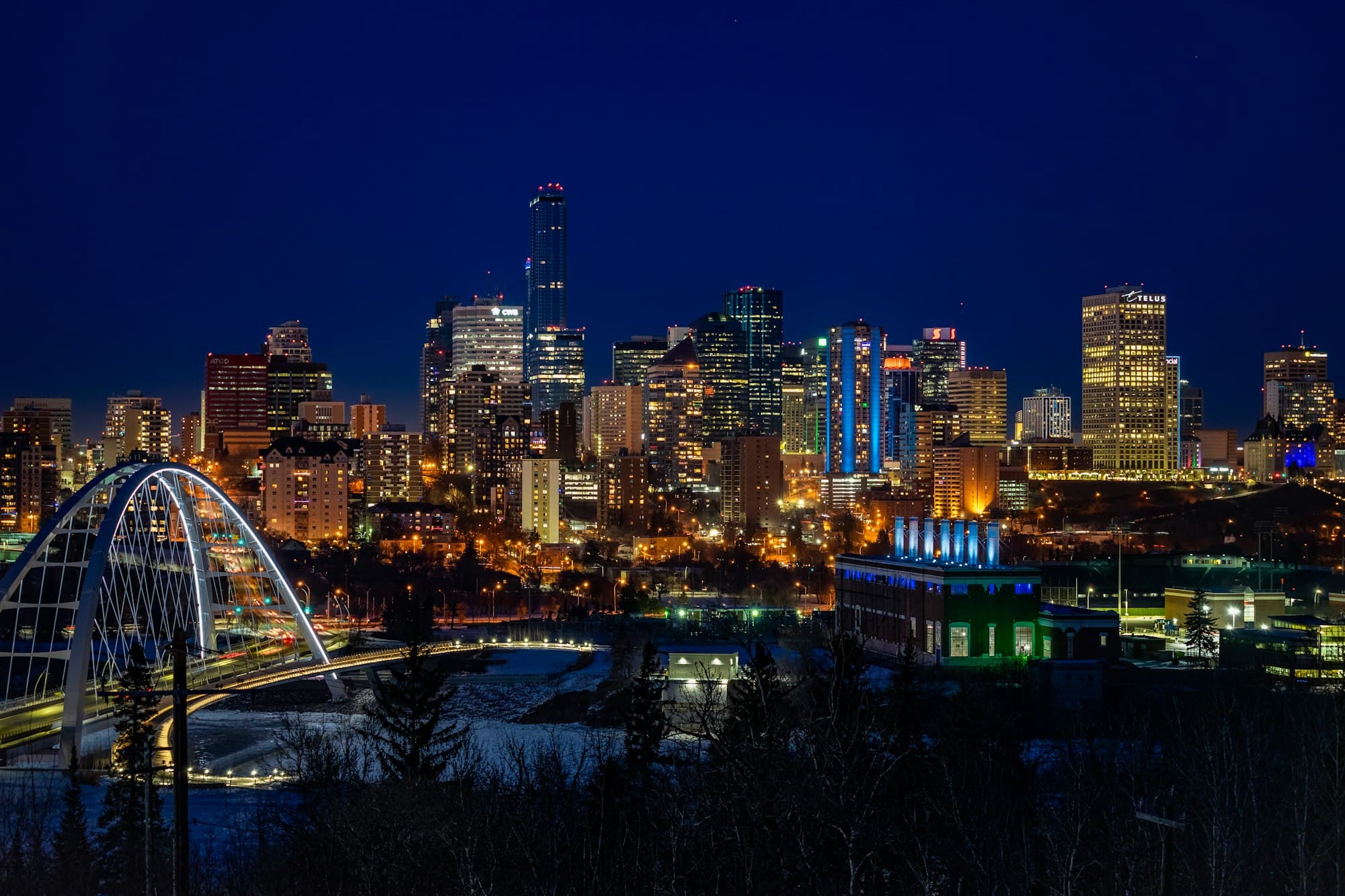 Edmonton's downtown skyline lit up at night above the river valley