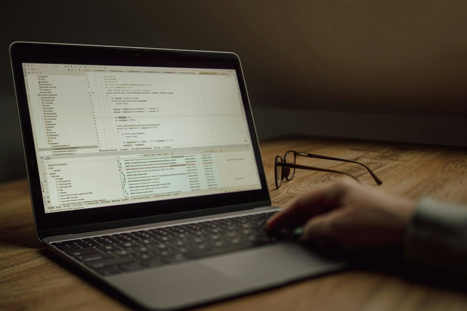 Hands on a laptop showing code, lit by a warm lamp at night
